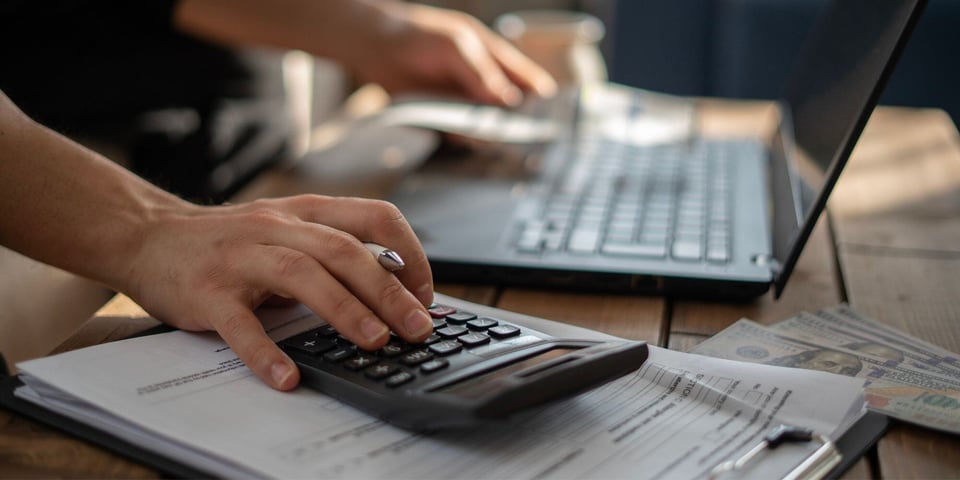 Person Using Calculator and Computer