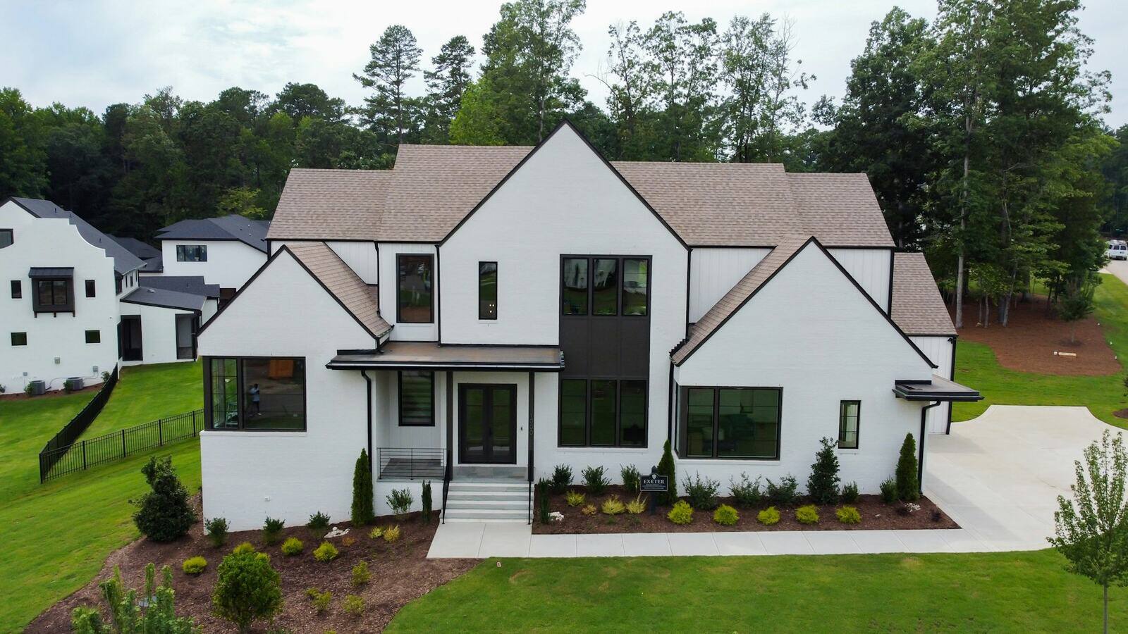 A modern two-story home with a sleek, minimalist design. The exterior features a white-painted brick façade with black-framed windows.